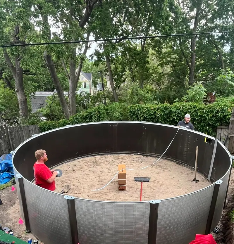 Pool Rx crew standing inside a newly set steel above-ground pool wall on a smooth sand base