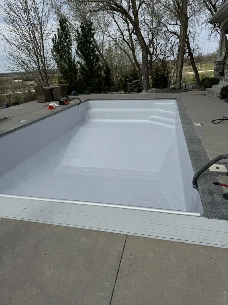 New grey-white vinyl liner installed in an empty rectangular in-ground pool, with built-in steps